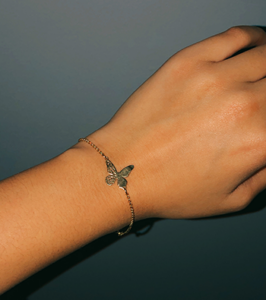 A wrist with a bracelet with a butterfly charm